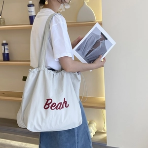 Detail of a cream nylon tote bag with red Beach print and drawstring closure