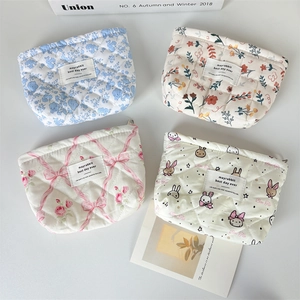 Flat lay of four quilted cotton makeup bags with floral and bunny patterns for travel