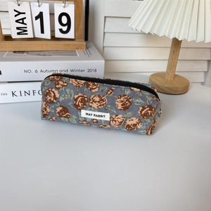 Detail of floral corduroy pencil case with May Rabbit label on a cozy desktop