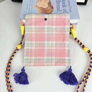 Detail of checkered crossbody bag with purple tassels and yellow rope strap