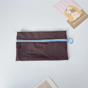 Detail of checkered nylon pouch with contrast blue zipper and pink edge trim