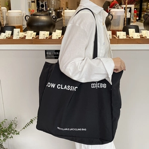 Minimalist black large capacity canvas tote bag with white lettering for daily commute