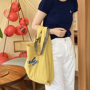 Casual large yellow nylon tote bag with blue nudy logo and wide grey shoulder strap