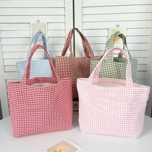Five assorted plaid canvas tote bags in various colors on a white desk with ins style décor