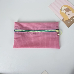 Close-up of pink checkered nylon pouch with contrasting blue zipper and round ring puller
