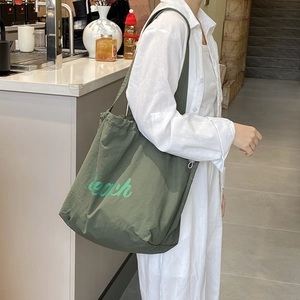 Detail of olive green nylon tote bag with reach lettering and wide shoulder strap