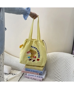 Detail of yellow canvas tote bag featuring cute cartoon bear embroidery and drawstring closure