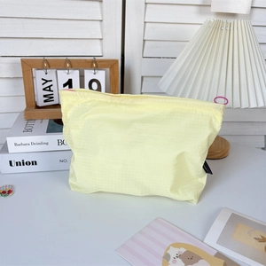 Close-up of a pale yellow checkered nylon storage bag with a pink ring zipper pull