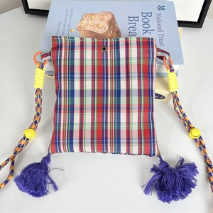 Detailed close-up of a colorful checkered fabric crossbody bag with purple tassels