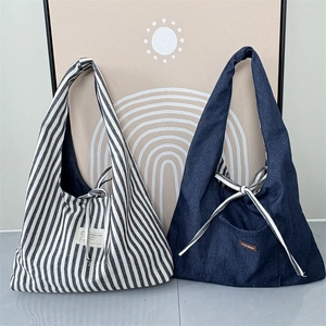 Close-up of retro striped canvas and denim tote bags with lace-up closure detail