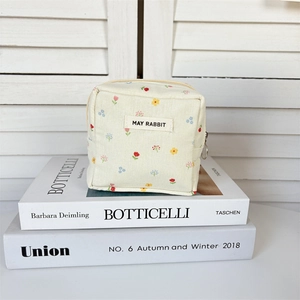 Gros plan d'une mini pochette florale avec fermeture éclair sur des livres
