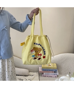 Detail of yellow canvas tote bag with cartoon bear embroidery and drawstring closure