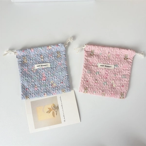 Dettaglio di sacchetti a coulisse trapuntati rosa e blu con stampe di animali e etichette