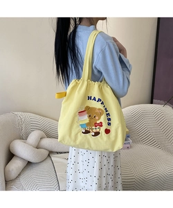 Detail of yellow canvas tote bag featuring bear embroidery and Happiness lettering