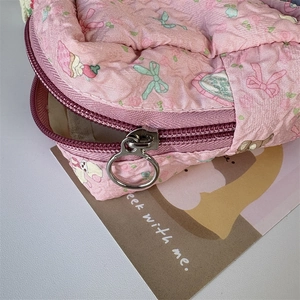 Close-up of pink quilted mini makeup pouch with cute strawberry prints and ring zipper