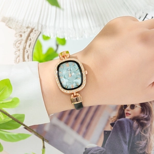 Close-up of elegant rose gold oval watch with diamond bezel and green marble dial