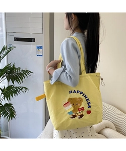 Detail of yellow canvas tote bag featuring cute bear embroidery and HAPPINESS lettering