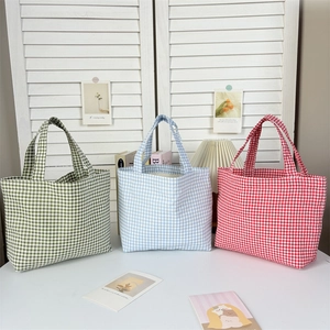 Detailed view of red, blue, and green checkered canvas tote bags in a home setting