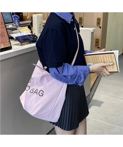 Lifestyle shot of large pink canvas tote bag with BAG print worn by a model
