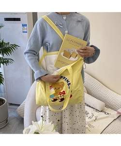 Close-up of yellow canvas tote bag featuring cute cartoon bear embroidery and drawstring detail