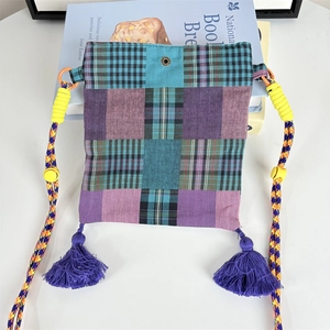Close-up of patchwork crossbody bag with purple tassels and woven rope strap