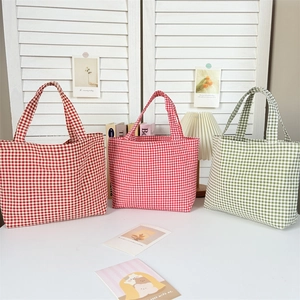 Close-up of three checkered canvas bento bags in red and green with cotton handles