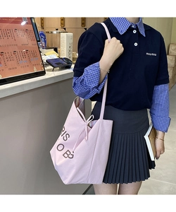 Detail of light pink canvas tote bag with letter print and slim shoulder strap