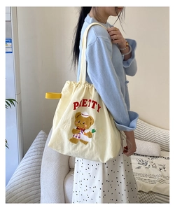 Detailed view of cream canvas tote bag featuring cute cartoon bear and drawstring closure