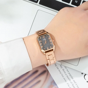 Détail de la montre rectangulaire en or rose avec bracelet en acier au bureau
