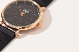 Close-up of rose gold watch case with black starry sky dial and silicone strap