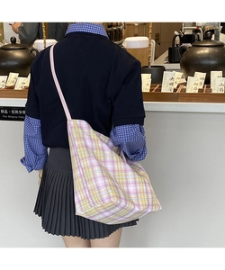 Rear view of a pink and yellow plaid tote bag with thin straps in a lifestyle setting