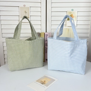 Detail of green and blue gingham canvas tote bags in a minimalist interior setting