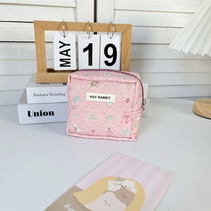 Close-up of pink quilted mini bag with cute cartoon rabbit and strawberry patterns