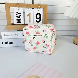 Detailed macro view of quilted floral makeup bag with metal zipper and MAY RABBIT tag
