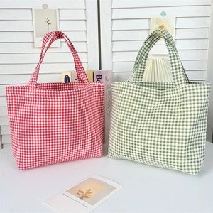 Detail of eco-friendly gingham tote bags in red and green canvas with durable handles