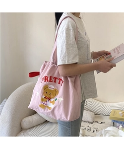 Close-up of pink canvas tote bag featuring cute cartoon bear embroidery and drawstring top