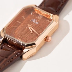 Macro shot of an octagonal rose gold case with brown crocodile leather strap and Tadi logo