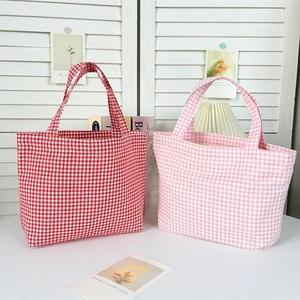 Detail of red and pink plaid canvas tote bags with durable handles and fabric texture