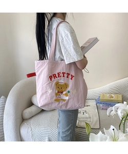 Detail of pink canvas tote featuring cute bear embroidery and red PRETTY lettering