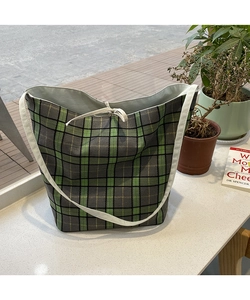 Detail of green plaid canvas tote bag with white drawstring closure and woven straps