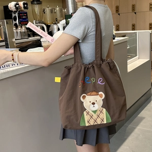 Detail of a brown canvas tote bag with a cute bear embroidery and drawstring closure