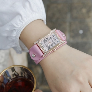 Close-up of a pink leather strap watch with rhinestone bezel and Roman numerals