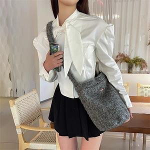 Détail du sac seau en peluche grise avec étiquette en cuir marron et texture douce et moelleuse