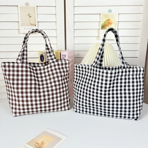 Detail of plaid canvas tote bags in brown and black with reinforced handles and large capacity