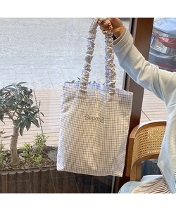 Dettaglio della borsa tote in tela a scacchi blu con manici a pieghe e ricami