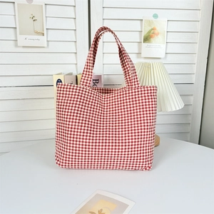 Detail of red gingham canvas tote bag handle and texture in a soft natural light setting