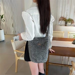 Détail du sac seau en peluche gris foncé avec une étiquette de logo en cuir marron