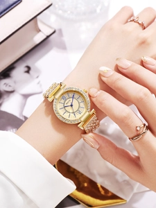Détail d'une montre de luxe dorée avec strass et chiffres romains portée au poignet