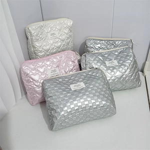 Close-up of quilted cosmetic bags in silver, pink, and beige with heart and checker patterns