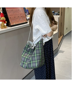Detail of green and black checkered canvas tote bag with slim shoulder straps